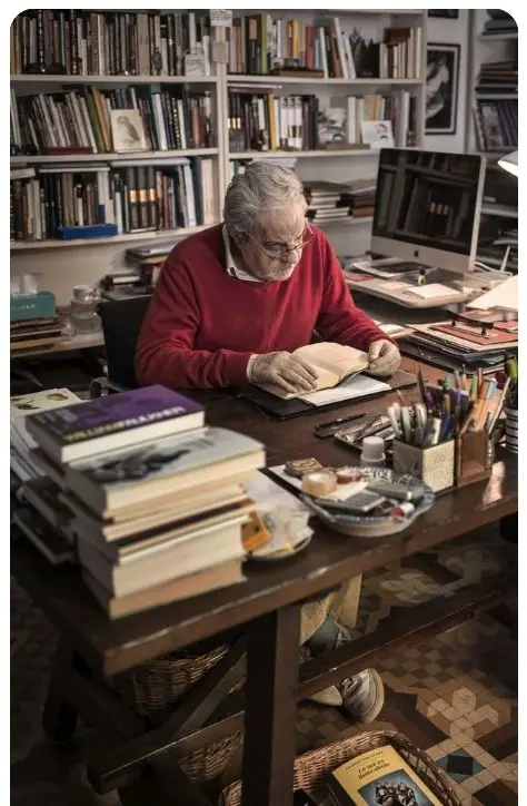 Professor working in a cluttered office, surrounded by books and papers
