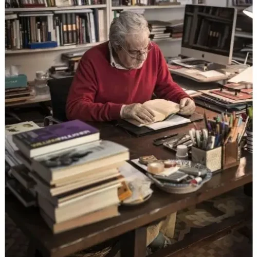 Professor working in a cluttered office, surrounded by books and papers